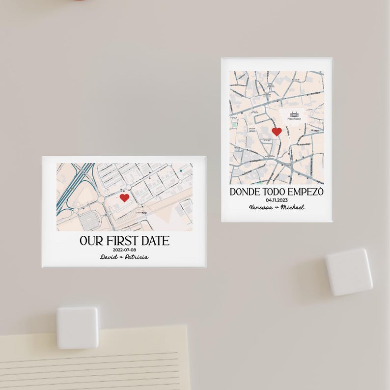 May include: Two rectangular white magnets with map designs. One magnet reads "OUR FIRST DATE" with a date and names. The other says "DONDE TODO EMPEZO" with a date and names. Both feature a red heart marking a location on the map.