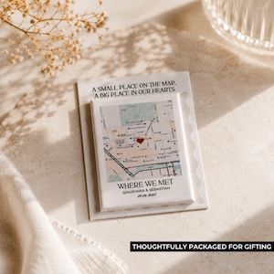 May include: A white rectangular magnet featuring a map design with a red heart marking a location. The text "WHERE WE MET" and names are below the map. The magnet is on a white card with the text "A SMALL PLACE ON THE MAP, A BIG PLACE IN OUR HEARTS".