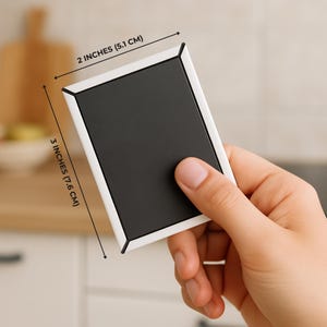 May include: A rectangular magnet with a black center and a white border. The magnet is 2 inches (5.1 cm) wide and 3 inches (7.6 cm) tall. The magnet is being held by a person.