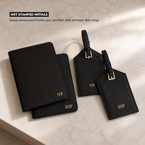 Peut inclure: Porte-passeport et &eacute;tiquettes de bagages en cuir noir avec initiales dor&eacute;es. Le porte-passeport et les &eacute;tiquettes ont une finition en relief profond. Le texte "HOT STAMPED INITIALS" est en haut.
