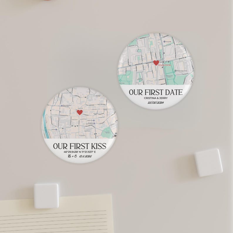 May include: Two round magnets with map designs. One says "OUR FIRST KISS" with coordinates and a date. The other says "OUR FIRST DATE" with names and a date. Both have a red heart marker.
