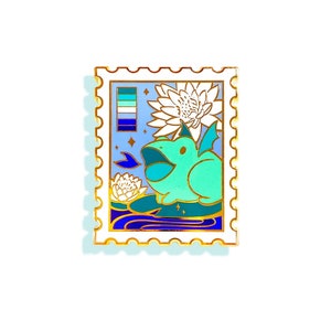 Puede incluir: Un pin de esmalte dorado con forma de sello de correos que presenta un dragón verde con alas azules y lengua azul, rodeado de nenúfares blancos y agua azul, sobre un fondo azul claro con una pequeña bandera del orgullo multicolor en la esquina superior izquierda.