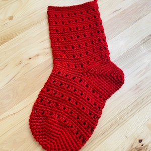 May include: A red crocheted Christmas stocking with a lacy pattern.