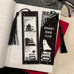 May include: Two black and white bookmark designs with a spooky theme. The first bookmark features a bookshelf with books and a spiderweb. The second bookmark features a ghost and a stack of books with the text "Spooky Book Club".