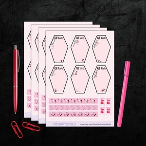 May include: Three sheets of pink paper with a set of six hexagonal to-do list stickers. Each sticker has a black outline and a white graphic of a knife and blood splatters. The stickers are labeled "Kill List." Below the stickers is a row of smaller stickers with a white graphic of a knife and blood splatters. The smaller stickers are labeled "To Do." The bottom of the sheet has the text "THE HAUNTED MALO" and a website address.