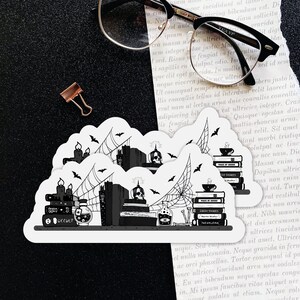 May include: Two black and white stickers featuring a stack of books with a skull, candles, and spiderwebs. The text on the stickers reads "Ghost Stories" and "Occult".