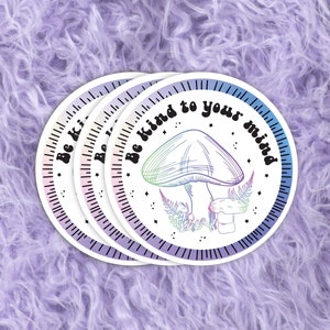 May include: Four pastel rainbow colored stickers with the text "Be kind to your mind" in a retro font. Each sticker features a line drawing of a mushroom with a star and fern design.
