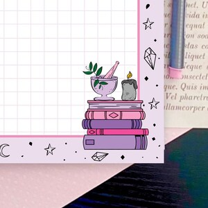 May include: A stack of purple and pink books with a mortar and pestle, a candle, and a sprig of green leaves on top. The background is a light purple grid with pink stars and diamonds.