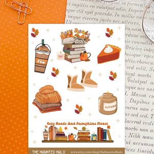 May include: A set of fall-themed stickers featuring a stack of books, a pumpkin spice latte, a slice of pumpkin pie, a pair of boots, a jar of candle, and a stack of books with pumpkins on a shelf. The text "Cozy Reads And Pumpkins Please" is included on the sticker.