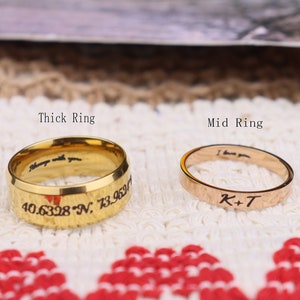 Puede incluir: Tres anillos de oro, oro rosa y plata con diferentes anchos. El anillo grueso tiene la inscripción "Always with you 40.6328 N, 73.959", el anillo mediano tiene la inscripción "I love you K+T" y el anillo delgado tiene la inscripción "VII-VIII-MMXIX".