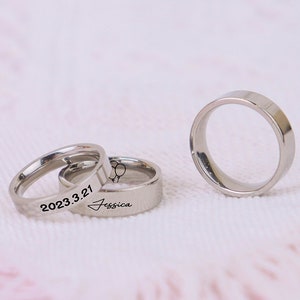 May include: Three silver rings with engraved text. The first ring has the date "2023.3.21" engraved on it. The second ring has the name "Jessica" engraved on it. The third ring is plain.