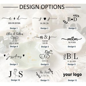 K&ouml;nnte beinhalten: Eine Sammlung von zw&ouml;lf verschiedenen schwarz-goldenen Grafikdesign-Optionen f&uuml;r personalisierte Schmuckschalen, die verschiedene Kombinationen aus Initialen, Daten, Blumenmotiven, Herzsymbolen und Schleifen zeigen, beschriftet von Design 1 bis 12.