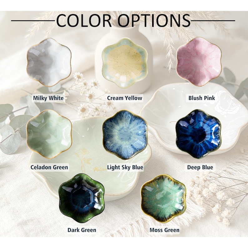 K&ouml;nnte beinhalten: Eine Sammlung von acht kleinen, blumenf&ouml;rmigen Keramikschalen, die mit dem Text COLOR OPTIONS pr&auml;sentiert werden. Die Schalen sind in den Farben Milchwei&szlig;, Cremegelb, Blassrosa, Seladongr&uuml;n, Hellhimmelblau, Tiefblau, Dunkelgr&uuml;n und Moosgr&uuml;n erh&auml;ltlich.