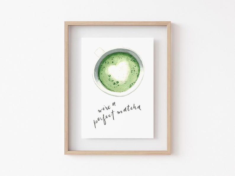 May include: A framed print with a watercolor illustration of a cup of green matcha with a heart-shaped design in the foam. The text "we're a perfect matcha" is written in black cursive below the cup.