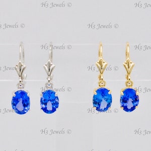 May include: Three pairs of oval blue gemstone earrings. The earrings are on a white background. The earrings are on a silver, gold, and gold hook.