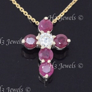 May include: A gold chain necklace with a pendant in the shape of a cross. The cross is adorned with five red ruby stones and a single clear diamond in the center.