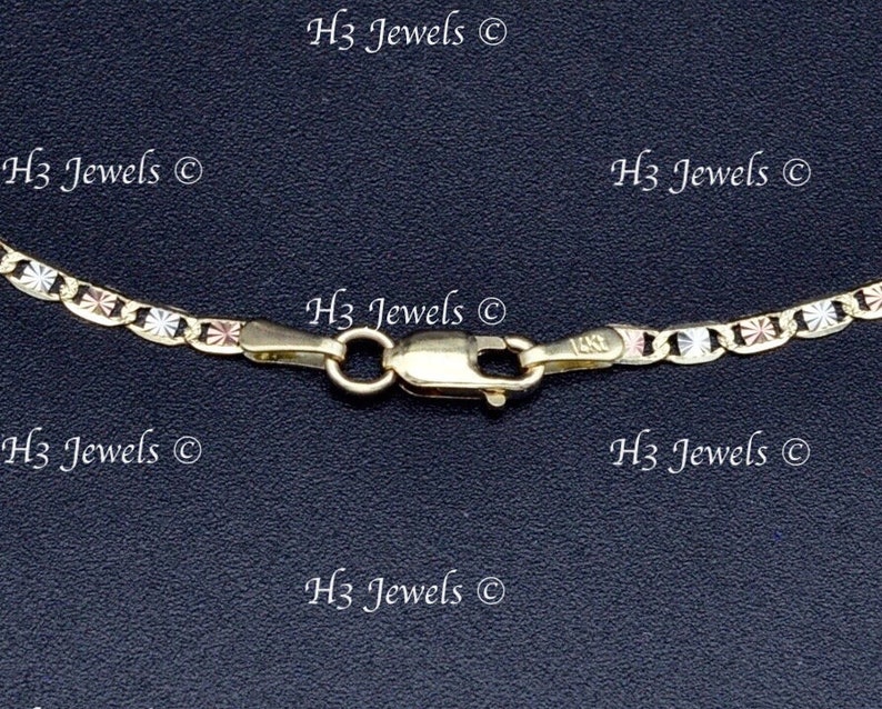 May include: A close-up of a gold chain necklace with a lobster clasp. The chain is made of three different colors of gold: yellow, white, and rose.
