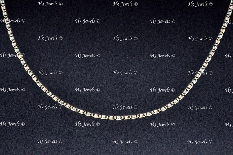 May include: A gold and silver chain necklace with a delicate design. The chain is made of small, round links and has a subtle shimmer.