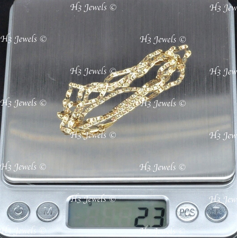 May include: A gold chain necklace on a digital scale, the scale reads 2.3 grams. The chain is on a white surface with the text "H3 Jewels" repeated multiple times.