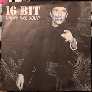 Puede incluir: Portada de álbum en blanco y negro para "16 Bit Where Are You?" con un hombre señalando al espectador. El título del álbum está en letras grandes y en negrita en la parte superior, con la pregunta debajo. El hombre viste ropa oscura.
