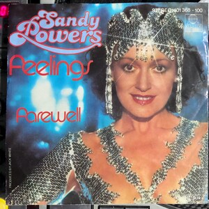 May include: A vintage vinyl record cover featuring Sandy Powers with the text Feelings and Farewell. The artist wears a silver sequined headpiece and matching top against a blue background. The Ariola logo and catalog number 101 368-100 appear.