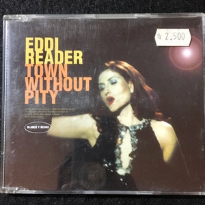 May include: A CD case with a black and white photo of a woman singing. The title of the CD is "Eddi Reader Town Without Pity" and the label is "Blanco y Negro".