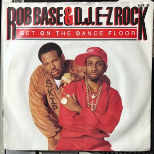 May include: A vintage record single by Rob Base & DJ E-Z Rock, featuring the song "Get On The Dance Floor". The record cover features a photo of the two artists, one wearing a brown jacket and the other wearing a red jacket and a baseball cap.