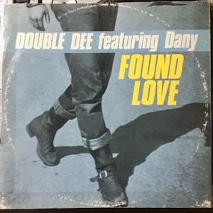 May include: A vintage vinyl record cover featuring a person wearing jeans and boots walking. The cover is blue and yellow with the text "DOUBLE DEE featuring Dany FOUND LOVE".