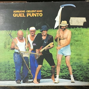 Peut inclure: Une pochette de disque vinyle vintage représentant un groupe de quatre hommes dans un champ. La pochette de l'album est pour l'album "Quel Punto" d'Adriano Celentano.