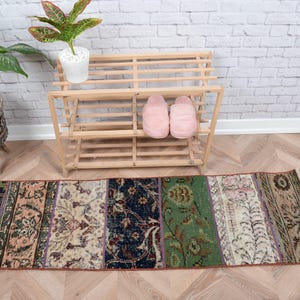 Puede incluir: Una alfombra de corredor de patchwork multicolor con una variedad de patrones florales. La alfombra está colocada sobre un suelo de madera delante de un zapatero de madera con zapatillas rosas en el estante superior.