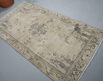 May include: A rectangular area rug featuring a light beige base color with intricate black line patterns. The design includes a central geometric medallion surrounded by scattered floral motifs and a detailed border with repeating linear elements.