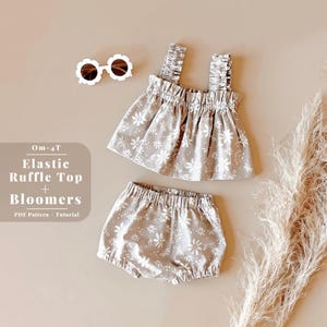 May include: A set of baby clothes in a floral print. The set includes a white tank top with elastic at the top and a pair of bloomers. The text "0m-4T Elastic Ruffle Top + Bloomers PDF Pattern - Tutorial" is printed on a white background.