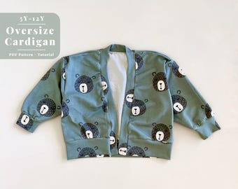 May include: A green cardigan with a bear print pattern. The cardigan is open in the front and has long sleeves. The text "5Y-12Y Oversize Cardigan PDF Pattern Tutorial" is printed on a white background.