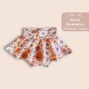 May include: A floral print skirt for babies and toddlers. The skirt is made of a soft, stretchy fabric and has a gathered waistband. The skirt is available in sizes 0m - 4T. The image includes the text "Skirt Bummies" and "PDF Pattern + Tutorial".