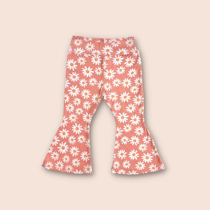 May include: A pair of coral-colored bell bottom pants with a white daisy print.