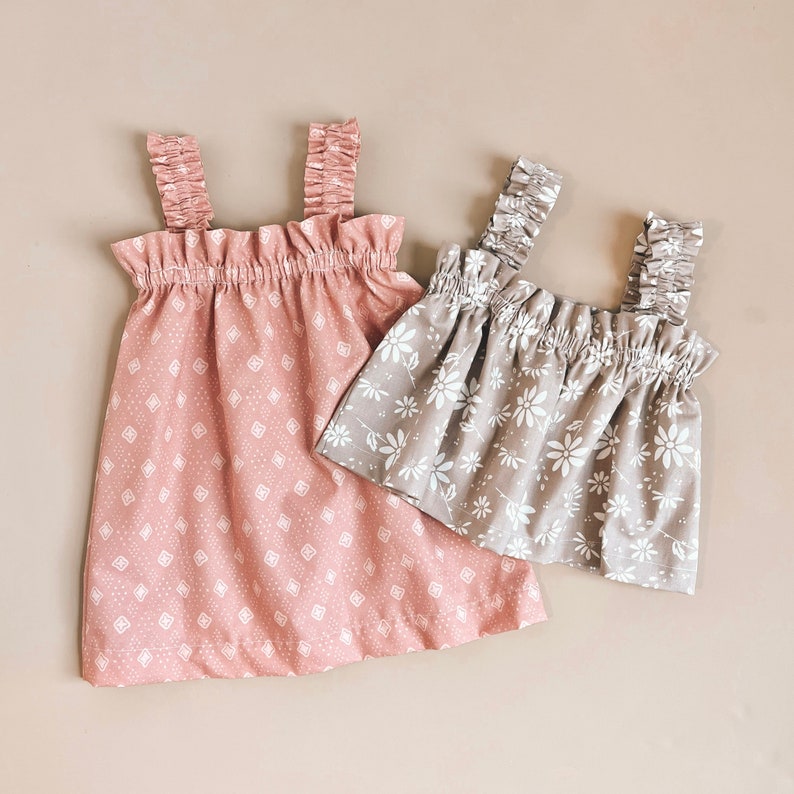 Puede incluir: Dos vestidos sin mangas con estampados florales. El vestido de la izquierda es rosa con un estampado geom&eacute;trico blanco. El vestido de la derecha es beige con un estampado floral blanco.