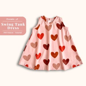 Könnte beinhalten: Ein rosa, ärmelloses Swing-Tankkleid mit einem Herz-Druck in Rot-, Orange- und Brauntönen. Das Kleid hat einen V-Ausschnitt und einen ausgestellten Rock. Der Text "Preemie - 4T Swing Tank Dress PDF Pattern - Tutorial" ist auf einem rosa Rechteck gedruckt.