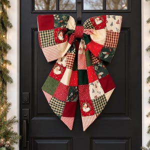 May include: A large decorative bow made of patchwork fabric featuring a variety of holiday-themed patterns including Santa Claus faces, evergreen trees, holly berries, red and green plaid, and striped designs in shades of red, green, and cream.