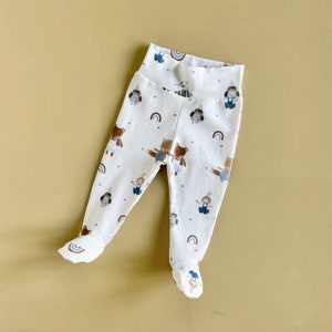 May include: White baby leggings with a colourful animal print featuring bears, rabbits, and owls. The leggings have a rainbow pattern and are made of soft, comfortable fabric.