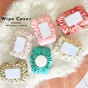 Pode incluir: Uma coleção de capas de tecido para lenços umedecidos em vários padrões e cores, incluindo floral, xadrez e verde-azulado. Cada capa tem uma abertura retangular branca. O texto "Wipe Cover Onesize PDF Pattern + Tutorial" é visível.