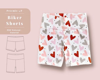 May include: A white pair of biker shorts with a heart print in shades of pink, red, and gray. The shorts have a wide waistband and are made of a stretchy fabric. The text "Preemie-4T Biker Shorts PDF Pattern + Tutorial" is visible in the top left corner of the image.