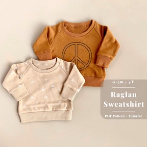 May include: Two raglan style baby sweatshirts, one brown with a peace sign graphic and one beige with a white geometric pattern. The text "0-3m - 4T Raglan Sweatshirt PDF Pattern + Tutorial" is visible below the sweatshirts.