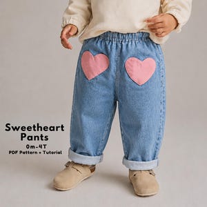 May include: Light blue denim pants with two pink heart-shaped patches on the back pockets. The pants have a rolled hem and an elastic waistband. The text "Sweetheart Pants" is visible on the left side of the image.