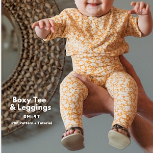 May include: A baby wearing a mustard yellow boxy tee and leggings set with a white floral pattern. The outfit is paired with brown sandals. The text "Boxy Tee & Leggings" and "0M-4T" is visible.