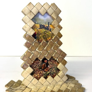 May include: A brown and beige woven picture frame with two photos. The top photo shows a black and white cat jumping in the air. The bottom photo shows a person's legs and feet walking on a path.