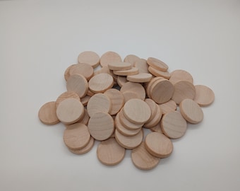 May include: A collection of small, natural wood discs. The discs are circular and have a light, unfinished appearance, with visible wood grain. They are scattered on a white background, possibly for a craft project or game.