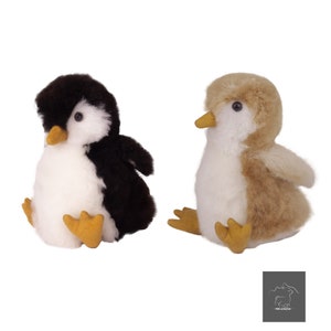 May include: Two plush penguin toys, one black and white and one brown and white. Both penguins are sitting with their feet forward and their wings out to the side.