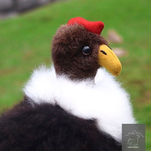 Puede incluir: Un juguete de peluche de un cóndor andino con cabeza roja, plumas marrones, un cuello blanco y un pico amarillo.