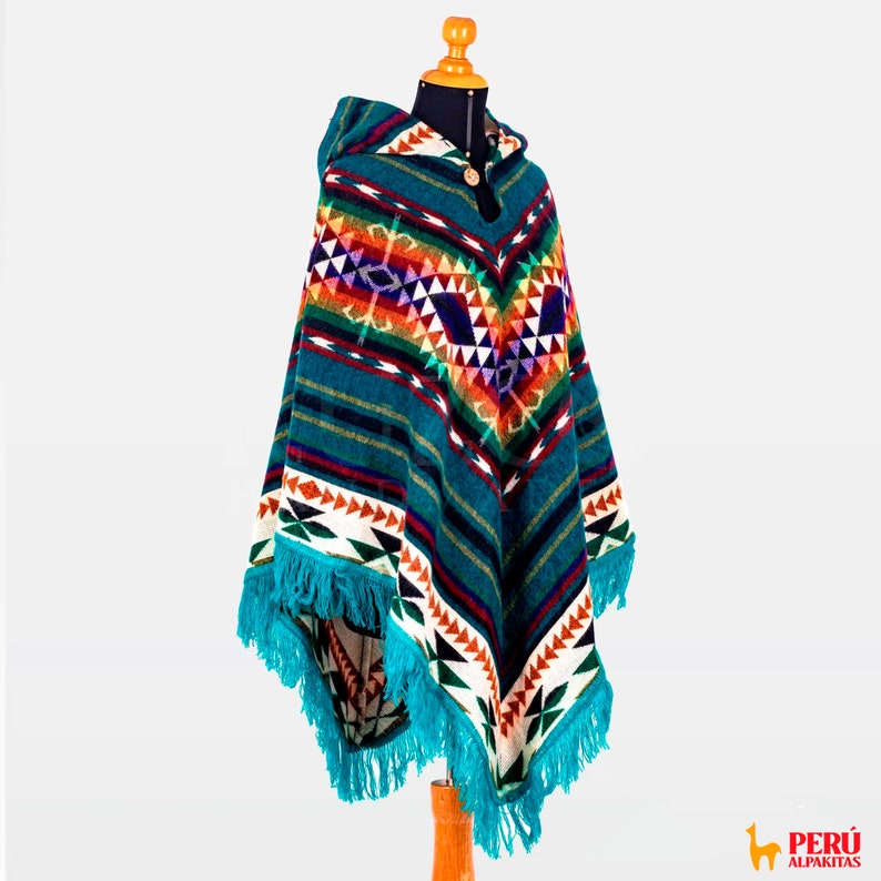 May include: A turquoise blue alpaca wool poncho with a colorful geometric pattern and fringe. The poncho has a hood and a wooden button closure.