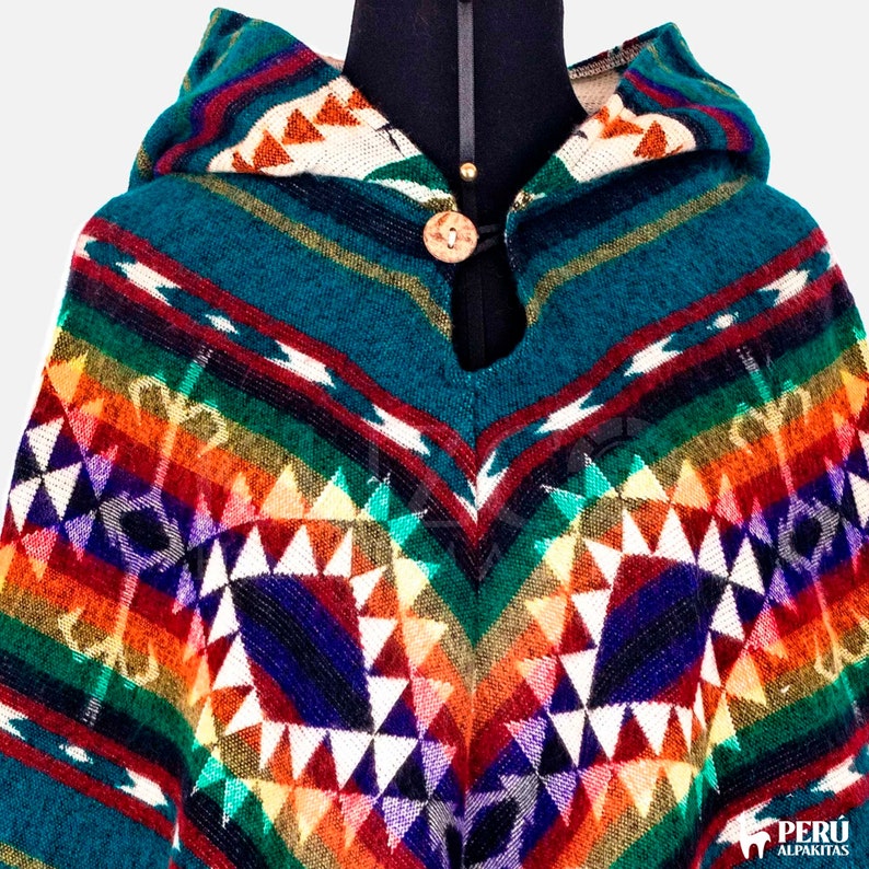May include: A teal blue hooded poncho with a colorful geometric pattern in shades of red, orange, yellow, green, blue, purple, and white. The poncho has a wooden button closure at the neck.